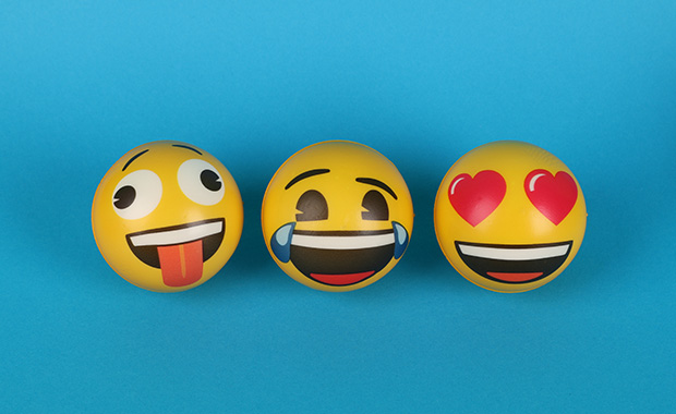 Three balls painted to look like emojis against a blue background