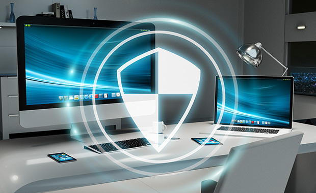 A desk setup with multiple devices, including a desktop computer, laptop, tablet, and smartphone, displaying a digital security shield overlay.