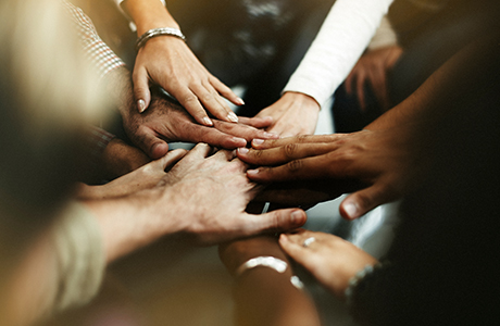 hands joining in the center of group of diverse people