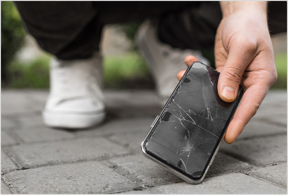 Hand picking up dropped smartphone with cracked screen