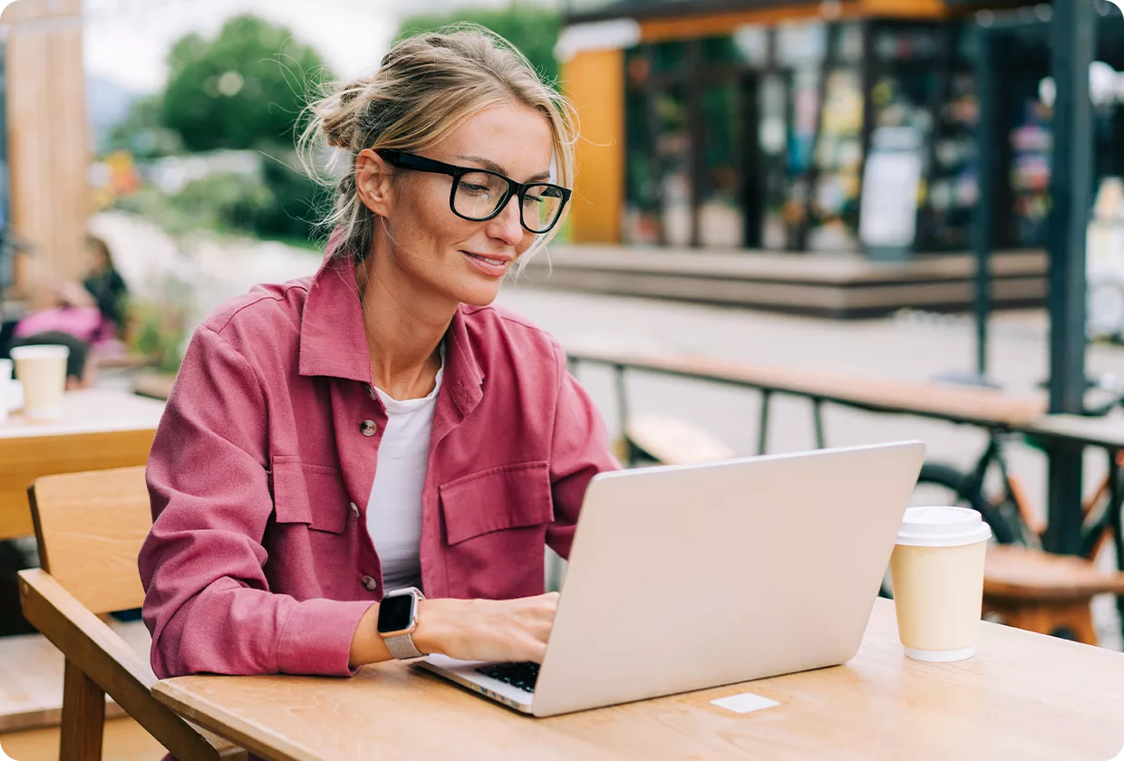 Woman working on laptop outdoors and smiling