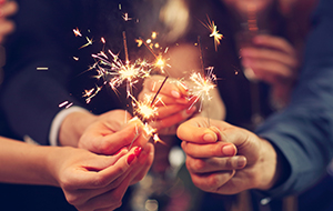 A group of people holding sparklers while celebrating together.